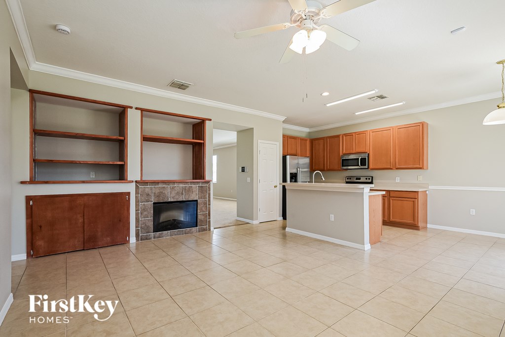 A spacious living room with a fireplace and a kitchen area in the background.