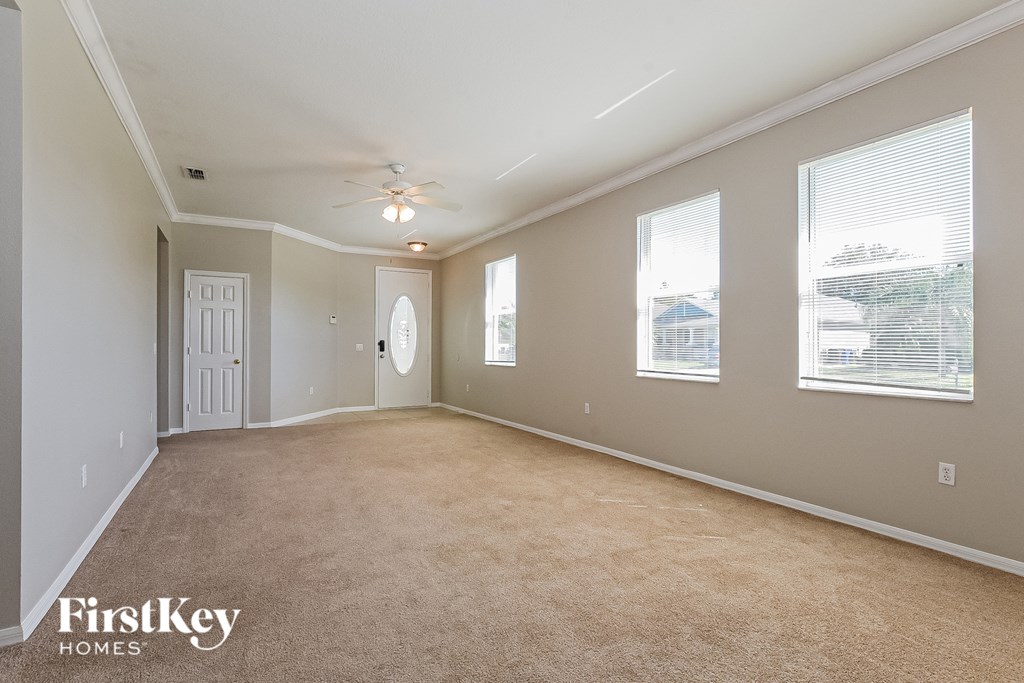 A spacious room with a carpeted floor and a ceiling fan.