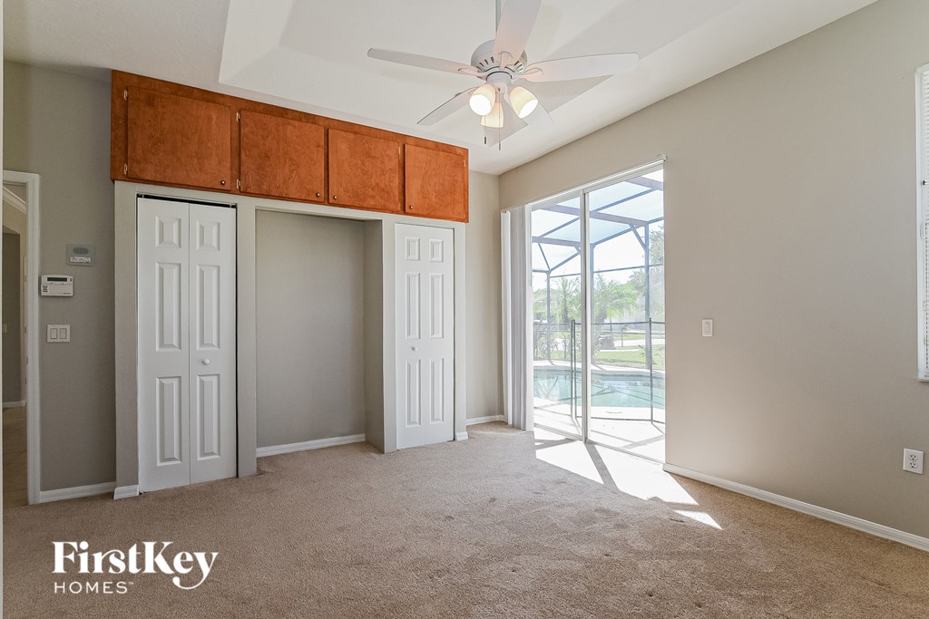 A room with a ceiling fan and a sliding glass door leading to a balcony.