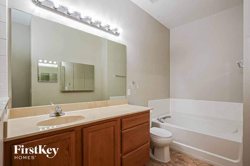 A bathroom with a wooden vanity and a white bathtub.