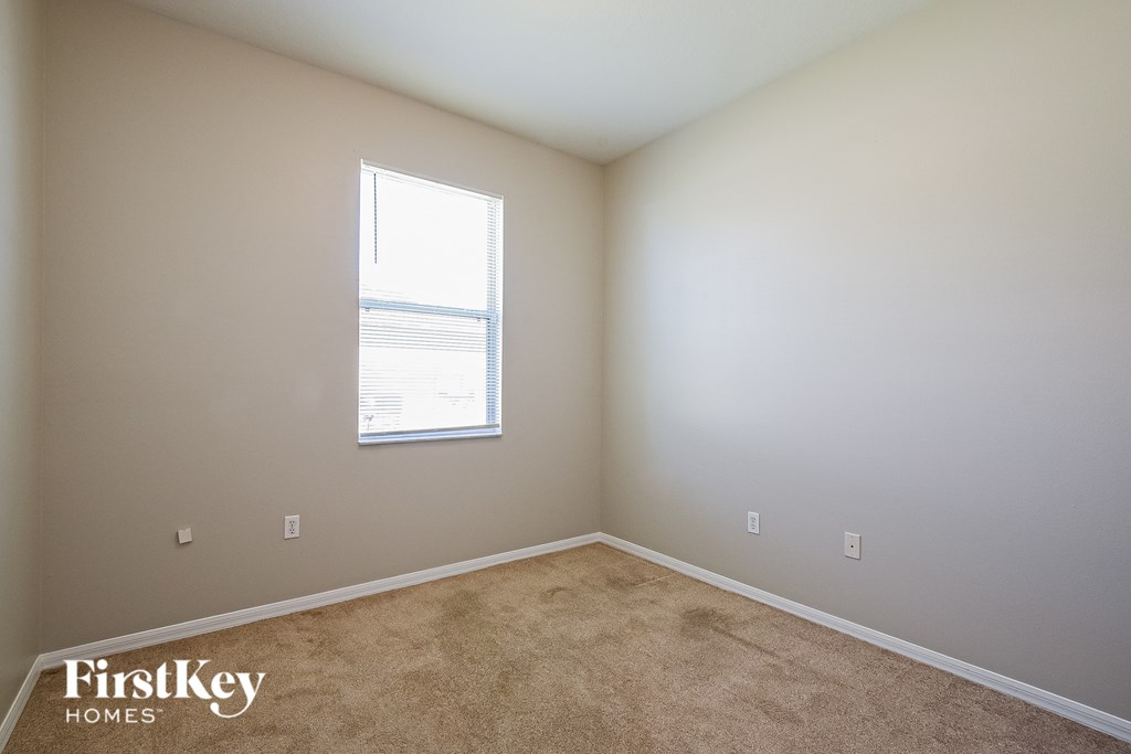 A room with a window and a carpeted floor.