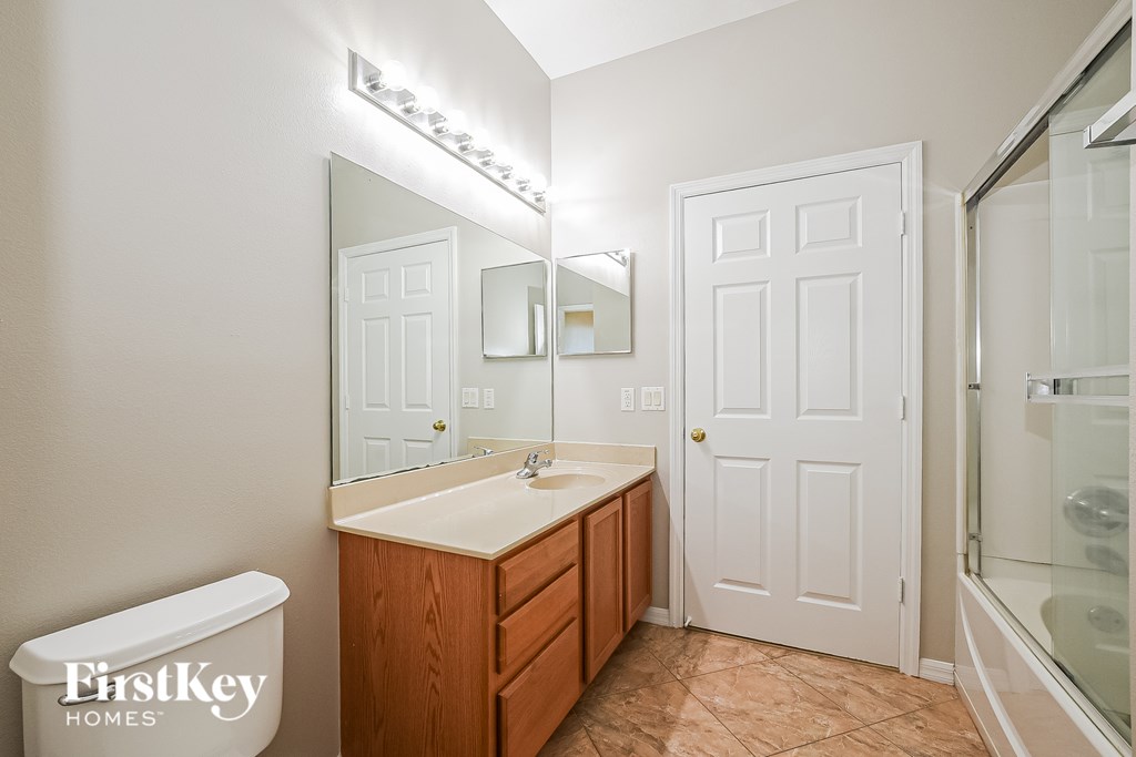 A bathroom with a sink, mirror, and a toilet.
