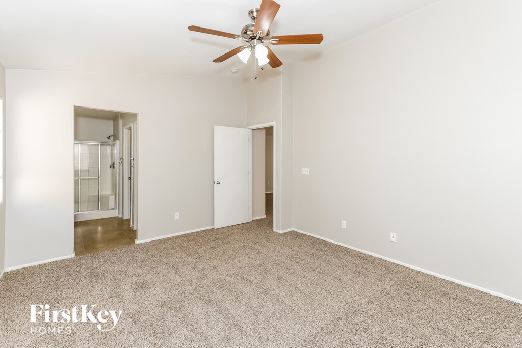 A spacious room with a ceiling fan and beige carpeting.