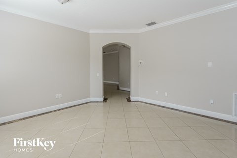 an empty living room with tiled flooring and a door to the hallway