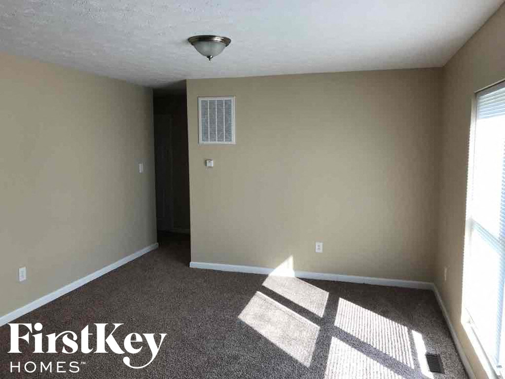 A room with a carpeted floor and a window letting in sunlight.