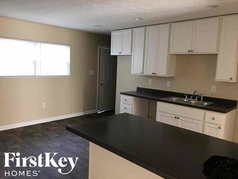 A kitchen with a black countertop and white cabinets.