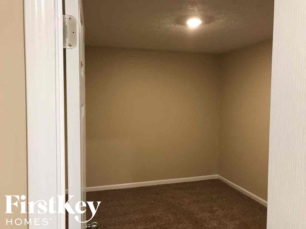 A carpeted room with a white door and a FirstKey Homes logo.