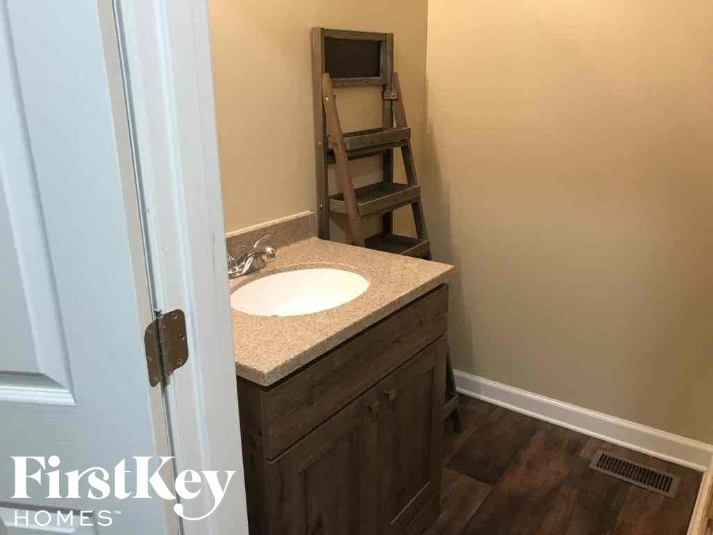 A bathroom with a sink and wooden floors.