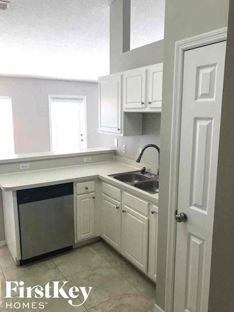 A kitchen with white cabinets and a dishwasher.