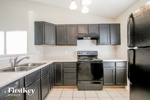 A kitchen with black cabinets and appliances.