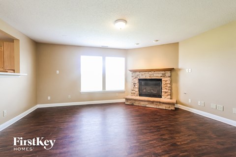 A spacious living room with a fireplace and wooden floors.