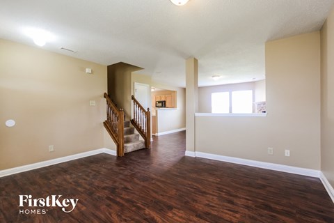 A spacious room with wooden floors and a staircase leading to another room.