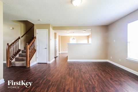 A spacious room with wooden floors and a staircase leading to another room.