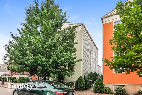 A green car is parked in front of a building with a sign that says "FirstKey Homes".