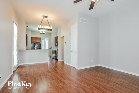 A spacious room with wooden floors and a ceiling fan.