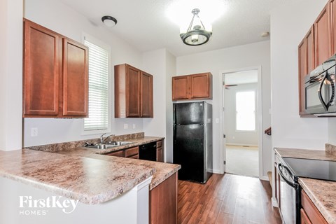 A kitchen with brown cabinets and a black refrigerator.