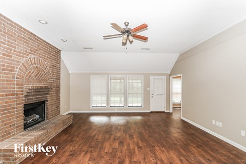 A spacious room with a brick fireplace and a ceiling fan.