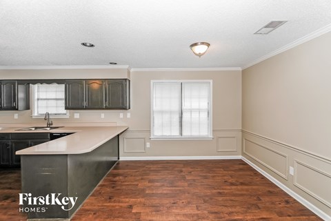 A kitchen with a wooden floor and a window with white blinds.
