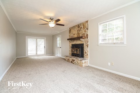 A spacious living room with a fireplace and a ceiling fan.