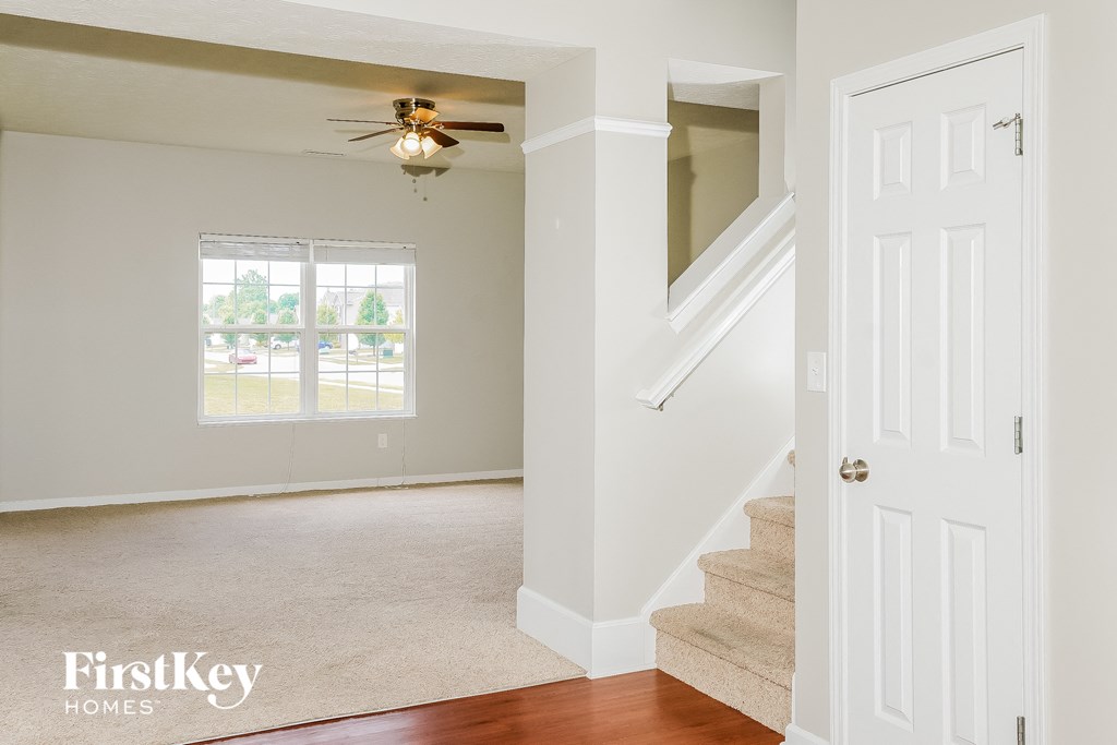 an empty living room with stairs and a ceiling fan