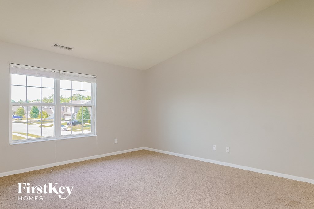 a bedroom with a large window and beige carpet