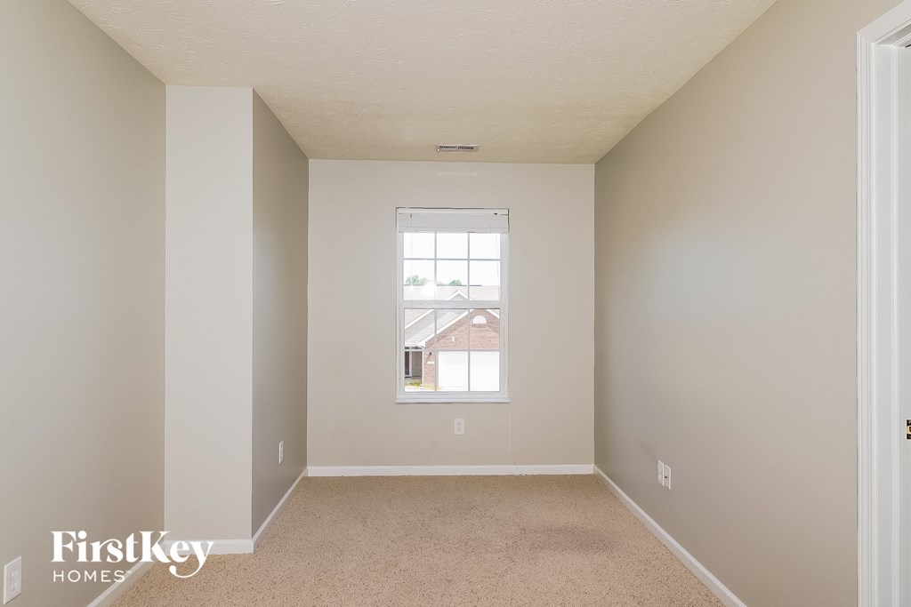 a bedroom with a window and a carpeted floor