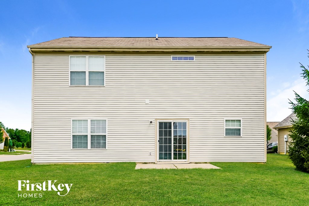 a side view of a white house on a green lawn