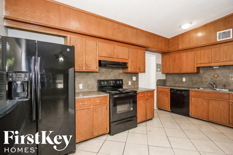 A kitchen with wooden cabinets and a black fridge.