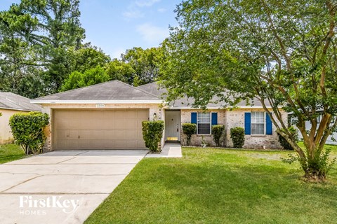 a home with a garage door and a lawn and trees