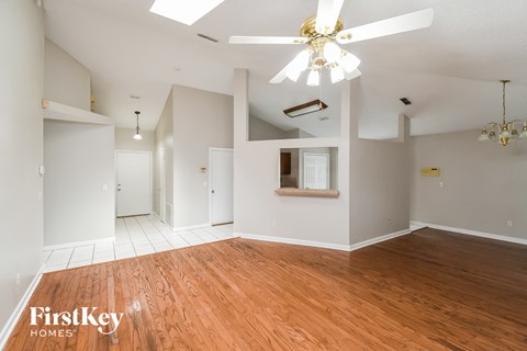 an empty living room with wood floors and a ceiling fan