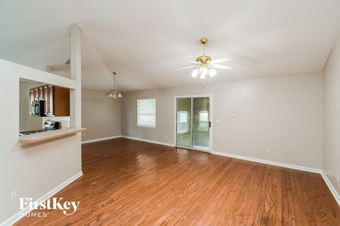 an empty living room with wood floors and a ceiling fan