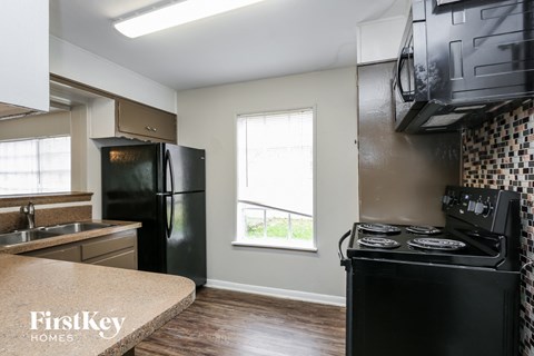 A kitchen with a black fridge and stove top oven.