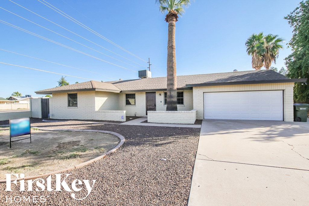 a white house with a palm tree and a driveway