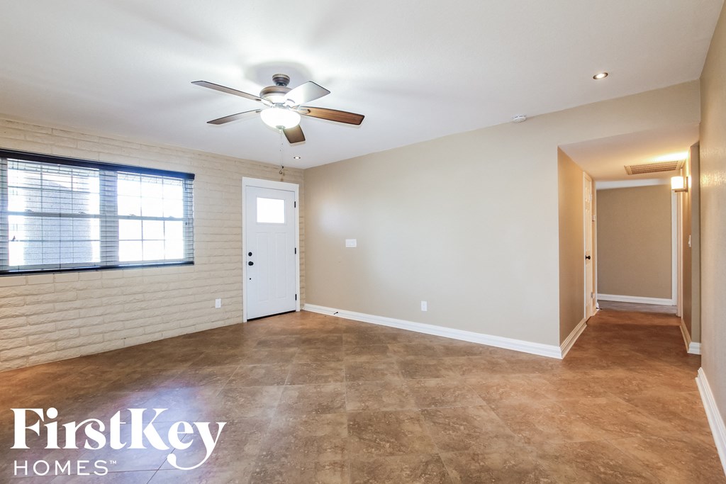 an empty living room with a ceiling fan and a window