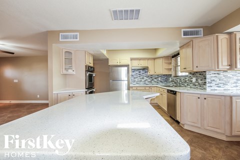 a kitchen with a large white counter top and a stainless steel refrigerator