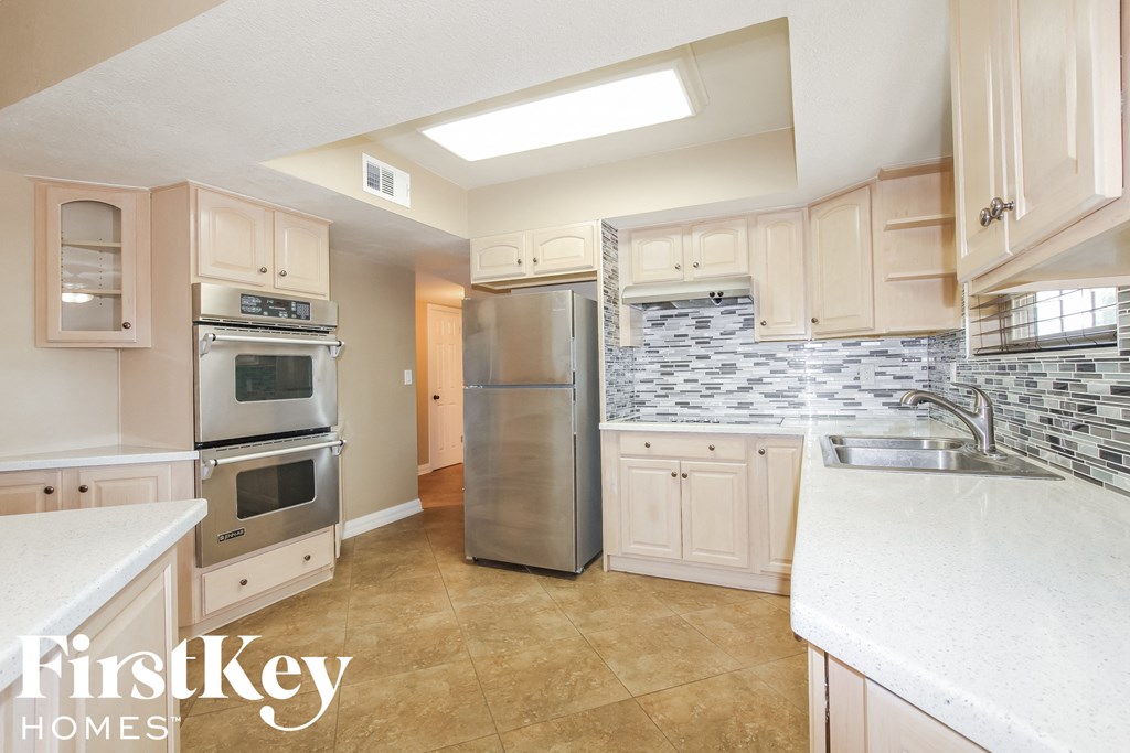 a white kitchen with stainless steel appliances and white counter tops