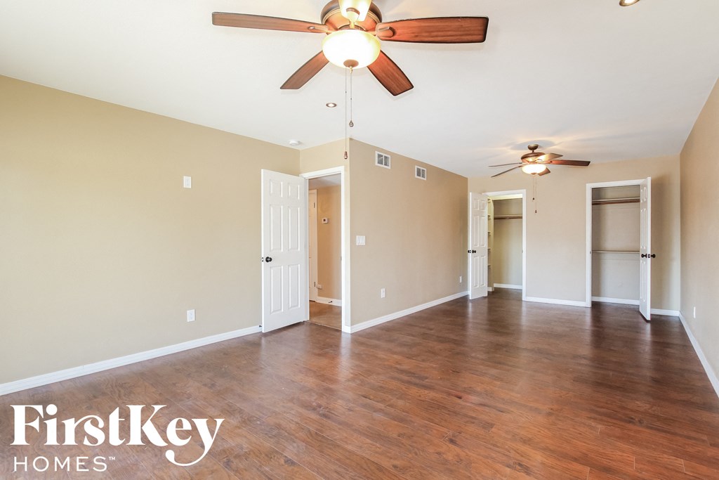 an empty living room with wood floors and a ceiling fan
