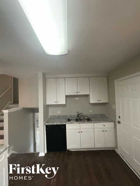 A kitchen with white cabinets and a black dishwasher.