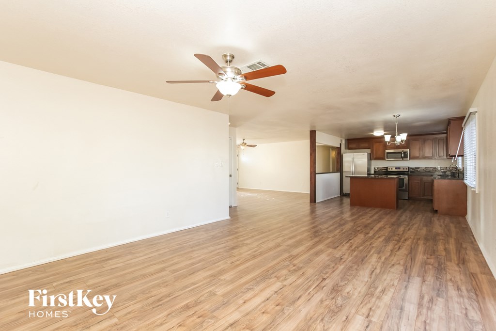 an open living room and kitchen with wood flooring and a ceiling fan