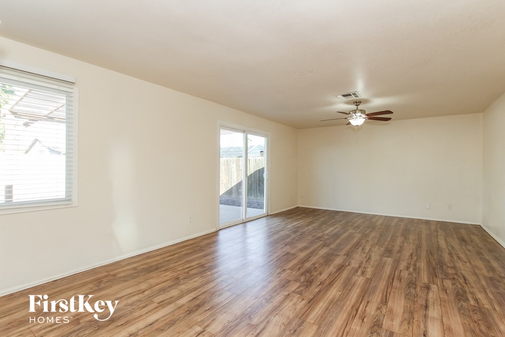 an empty living room with wood floors and a ceiling fan