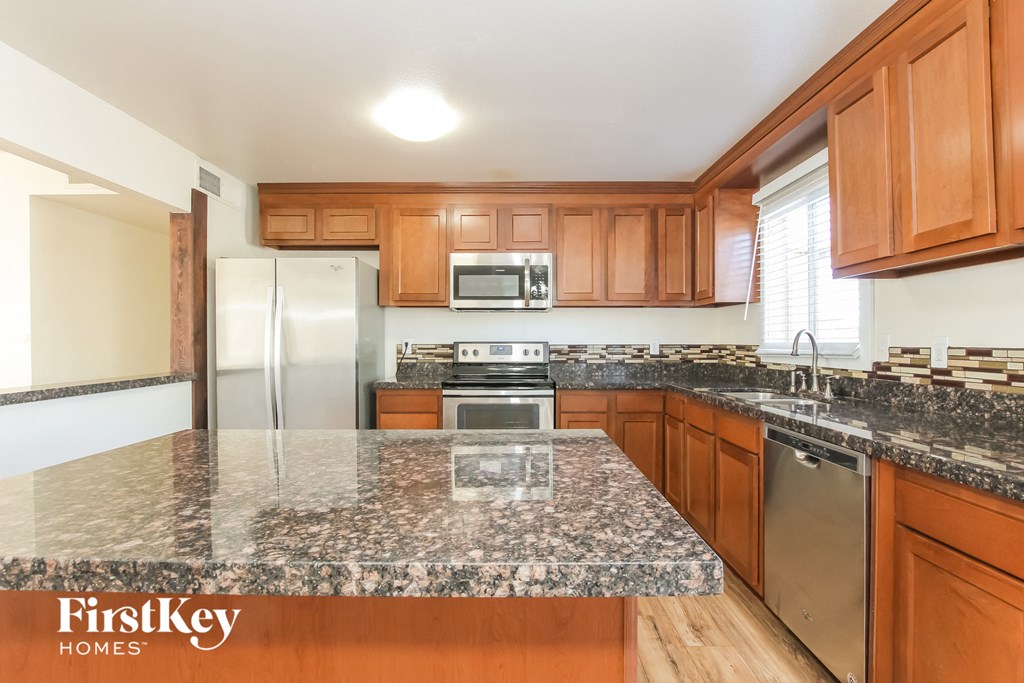 a kitchen with granite counter tops and wooden cabinets