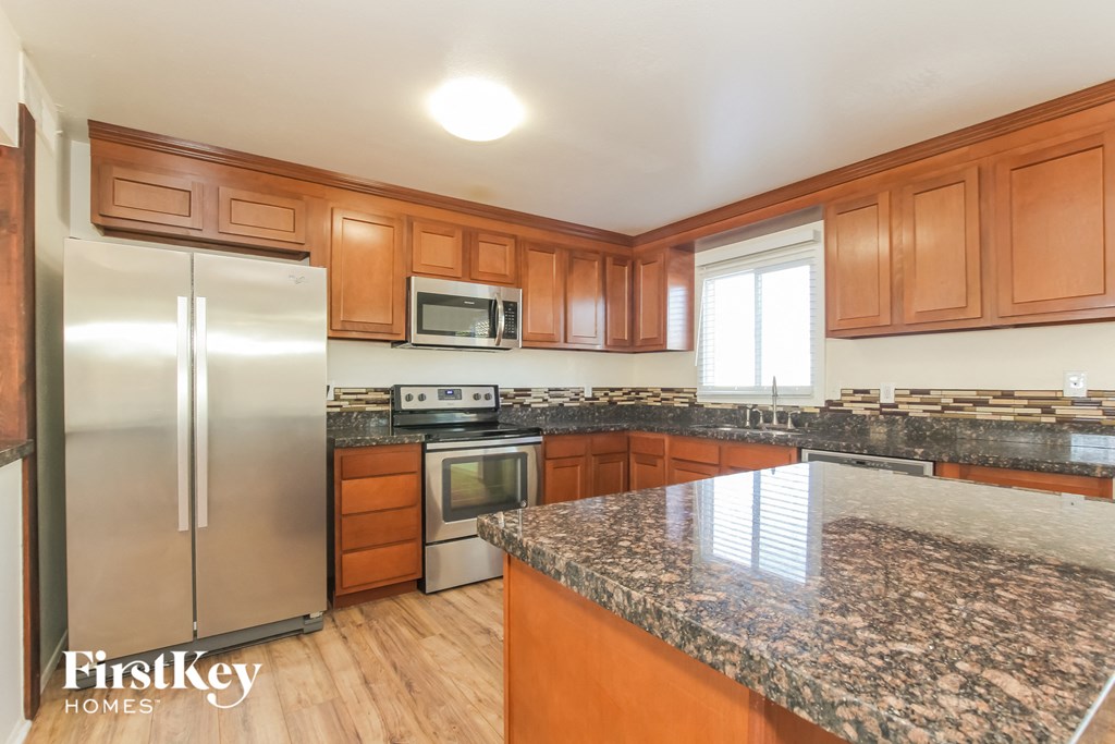 a kitchen with wooden cabinets and granite counter tops and stainless steel appliances