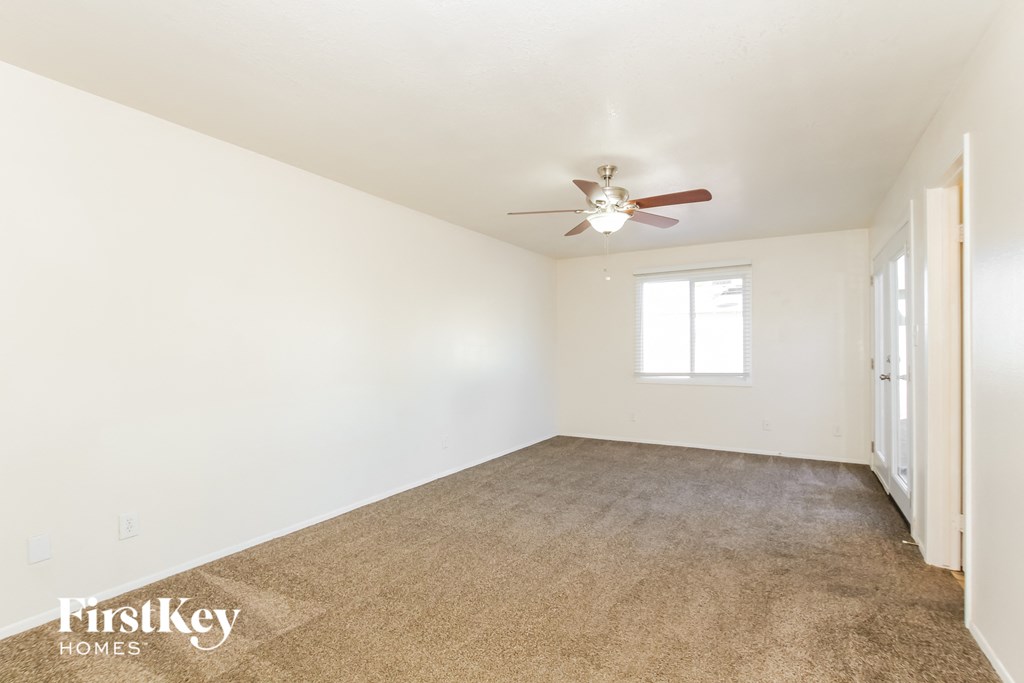 a living room with white walls and a ceiling fan