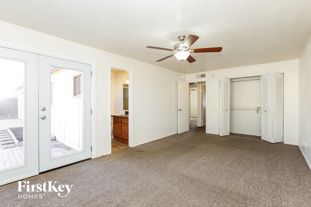 a living room with a ceiling fan and a door to a bathroom