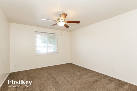 the living room of a home with carpet and a ceiling fan