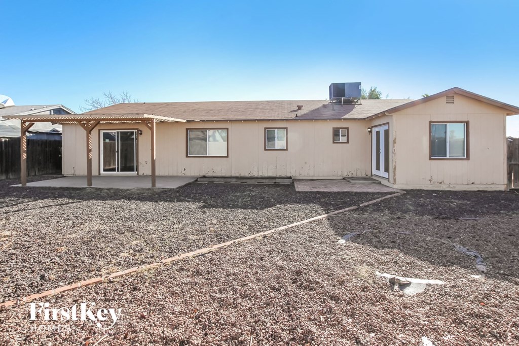 a beige house with a lot of gravel and a driveway