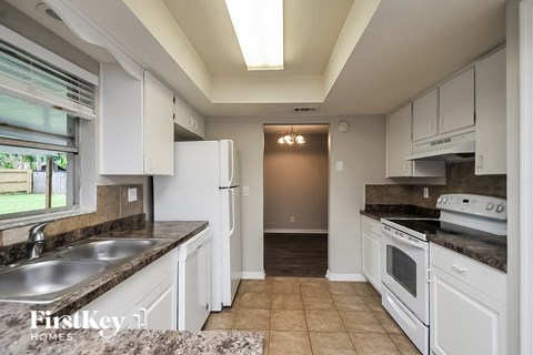 a kitchen with white cabinets and white appliances and a sink