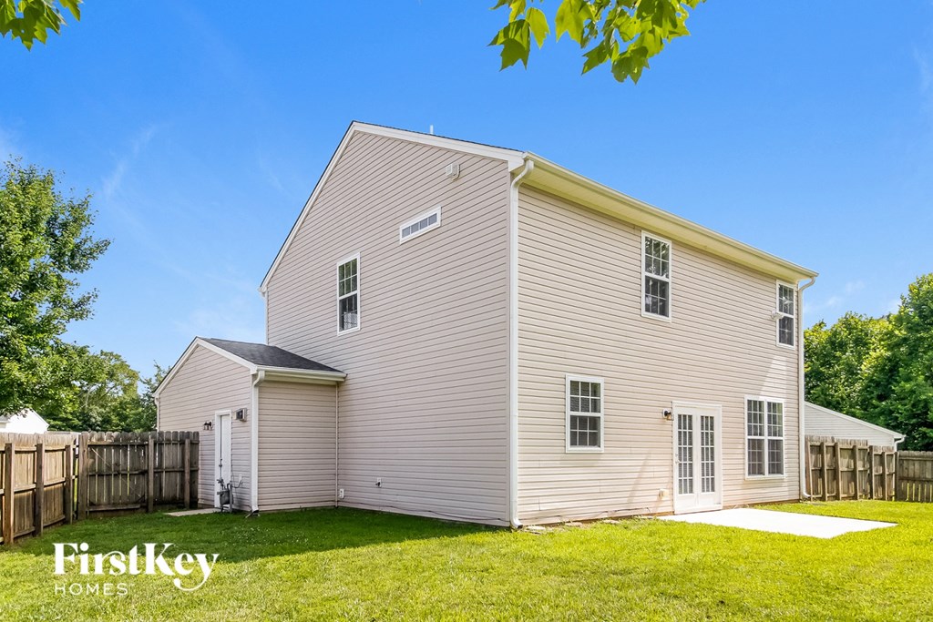 a small white house with a wooden fence and a yard