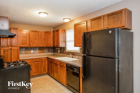 a kitchen with wooden cabinets and a black refrigerator