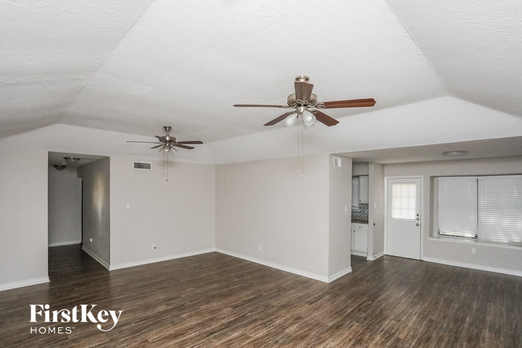 A spacious room with a ceiling fan and wooden flooring.